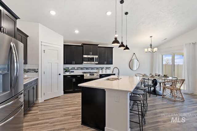19126 Red Eagle Way, Caldwell, ID 83605 - kitchen with stainless steel appliances, a sink, wood finished floors, decorative backsplash, and vaulted ceiling
