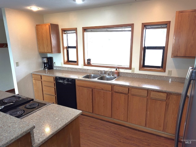 kitchen with light stone countertops, black appliances, sink, and dark hardwood / wood-style floors