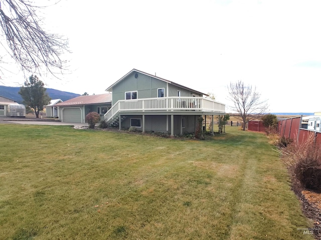 rear view of property featuring a yard, a wooden deck, and a garage