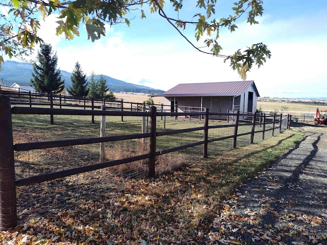 view of yard featuring a mountain view, an outdoor structure, and a rural view