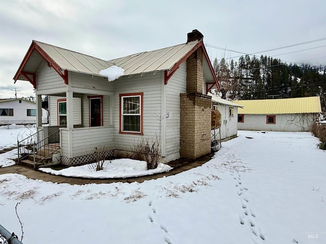 view of front of property featuring a standing seam roof, a chimney, and metal roof