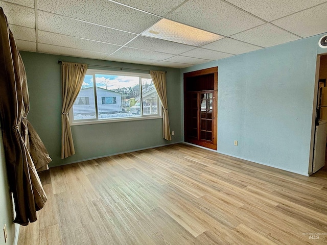 spare room featuring a paneled ceiling and light wood finished floors