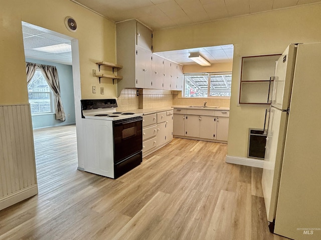 kitchen featuring light wood finished floors, electric range, freestanding refrigerator, light countertops, and a sink