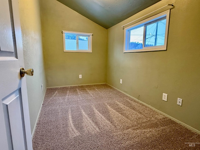 empty room featuring light carpet, baseboards, and lofted ceiling