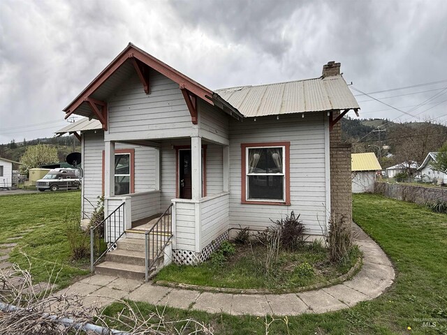 202 S Main St, Kooskia, ID 83539 - view of front of house with metal roof, a front yard, and a chimney