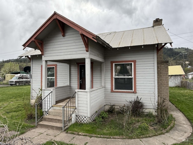 202 S Main St, Kooskia, ID 83539 - view of front facade with metal roof, a front yard, and a chimney