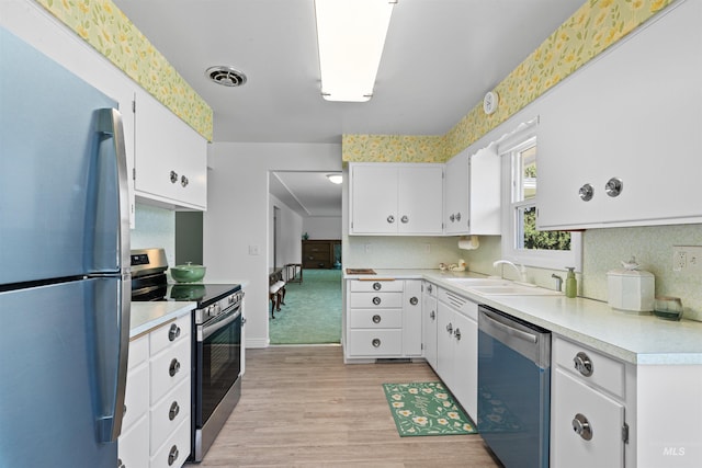 600 18th Ave, Lewiston, ID 83501 - kitchen with appliances with stainless steel finishes, a sink, light wood-style flooring, light countertops, and white cabinetry
