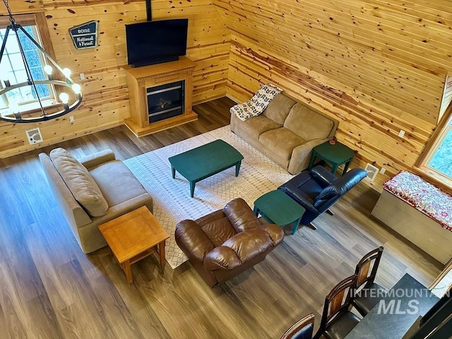 living room featuring wood walls, a wealth of natural light, a glass covered fireplace, and wood finished floors