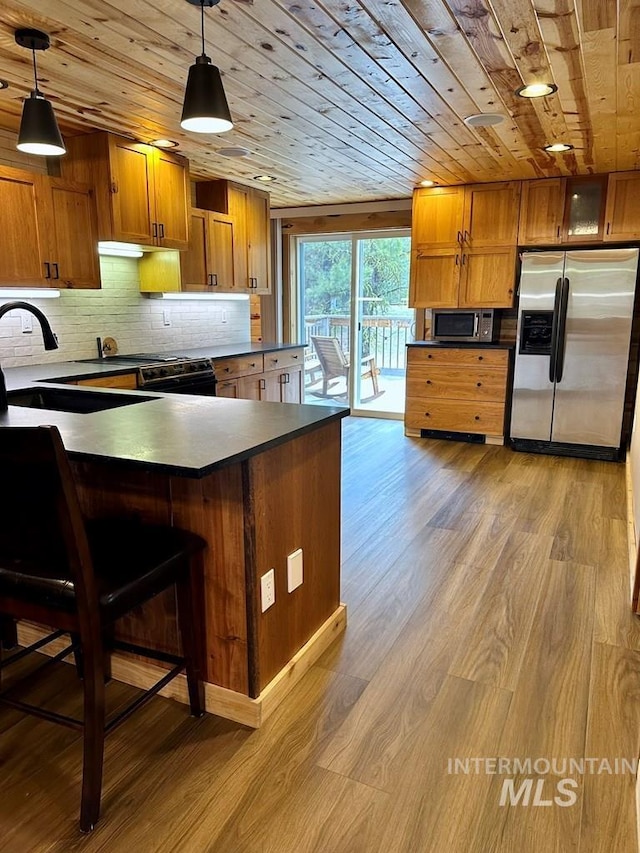 kitchen with wood ceiling, backsplash, brown cabinets, dark countertops, and appliances with stainless steel finishes