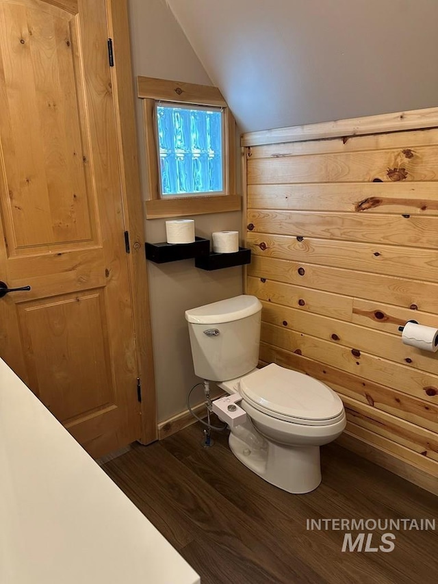 bathroom with toilet, lofted ceiling, and wood finished floors