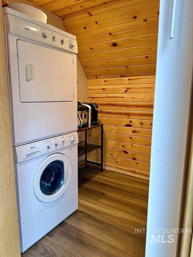 clothes washing area with stacked washer / dryer, wood ceiling, wooden walls, wood finished floors, and laundry area