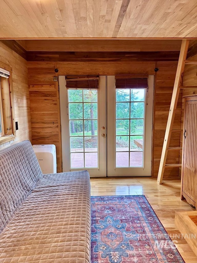 bedroom with multiple windows, wood walls, and access to exterior
