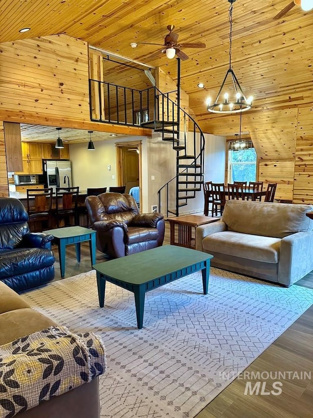 living area featuring wood ceiling, stairway, wood walls, and ceiling fan with notable chandelier