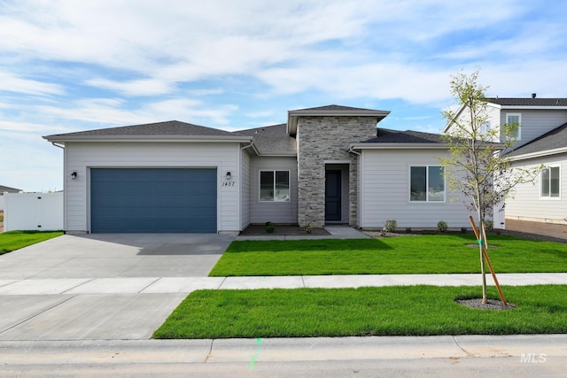 prairie-style house with stone siding, concrete driveway, a front lawn, and a garage