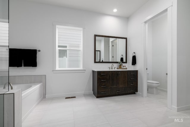 full bath with visible vents, toilet, vanity, baseboards, and a garden tub