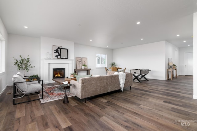 living area featuring dark wood-type flooring, a glass covered fireplace, baseboards, and recessed lighting