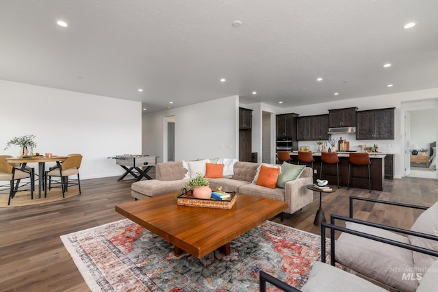 living area with baseboards, dark wood-type flooring, and recessed lighting