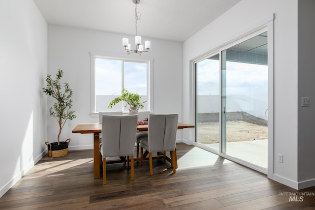 dining space with baseboards, wood finished floors, and a chandelier