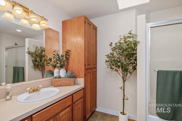 full bath featuring a shower with shower door, baseboards, and vanity