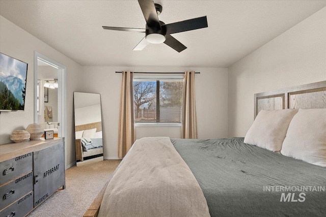 bedroom featuring baseboards, light carpet, ensuite bath, and a ceiling fan