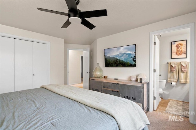 bedroom featuring ceiling fan, a closet, ensuite bathroom, and light carpet