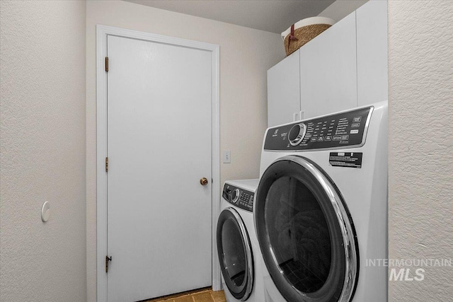 clothes washing area with cabinet space, a textured wall, and separate washer and dryer