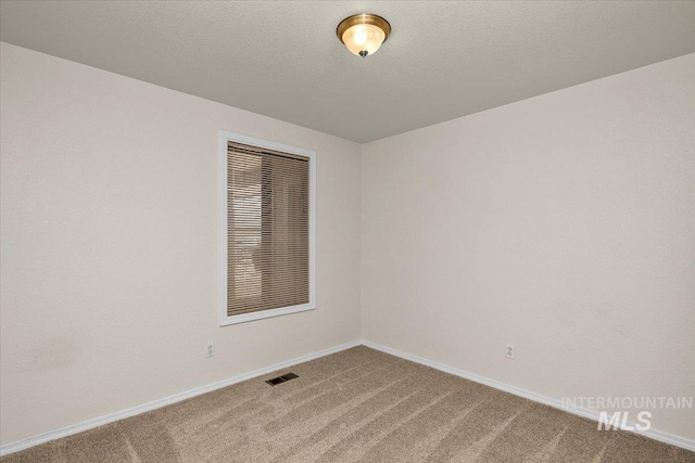 carpeted empty room featuring visible vents, baseboards, and a textured ceiling