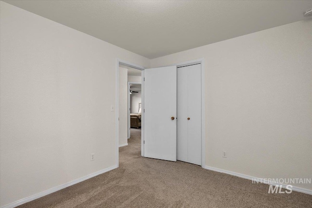 unfurnished bedroom with a closet, baseboards, carpet floors, and a textured ceiling