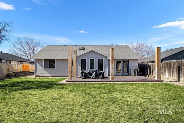 rear view of property featuring a wooden deck, a lawn, and a fenced backyard