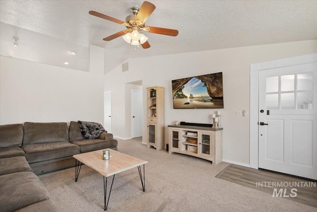 living area featuring baseboards, ceiling fan, vaulted ceiling, a textured ceiling, and carpet flooring