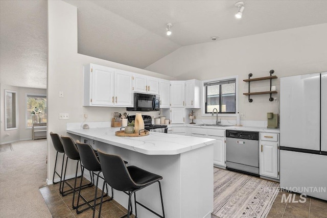 kitchen with a kitchen bar, a sink, stainless steel dishwasher, black microwave, and stove