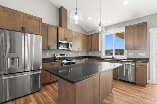 kitchen with light wood-style flooring, appliances with stainless steel finishes, vaulted ceiling, and a sink