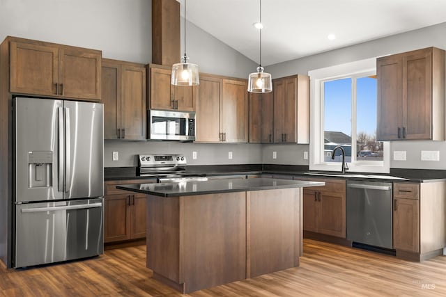 kitchen with lofted ceiling, stainless steel appliances, dark wood-type flooring, a sink, and dark countertops