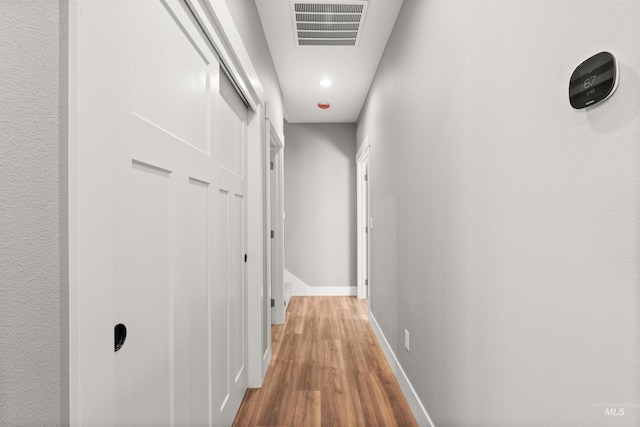 hallway with visible vents, baseboards, and wood finished floors