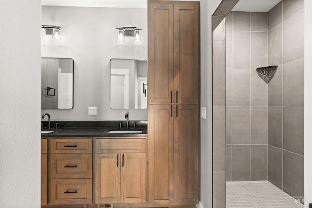 bathroom featuring double vanity, a sink, and tiled shower