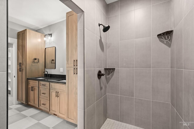 full bathroom with a sink, double vanity, a tile shower, and tile patterned floors