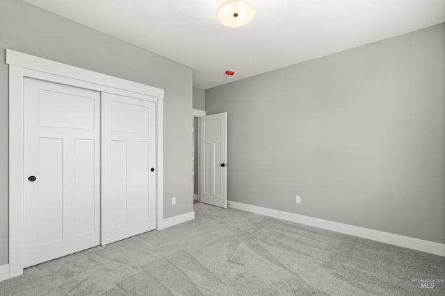 unfurnished bedroom featuring a closet, baseboards, and carpet flooring