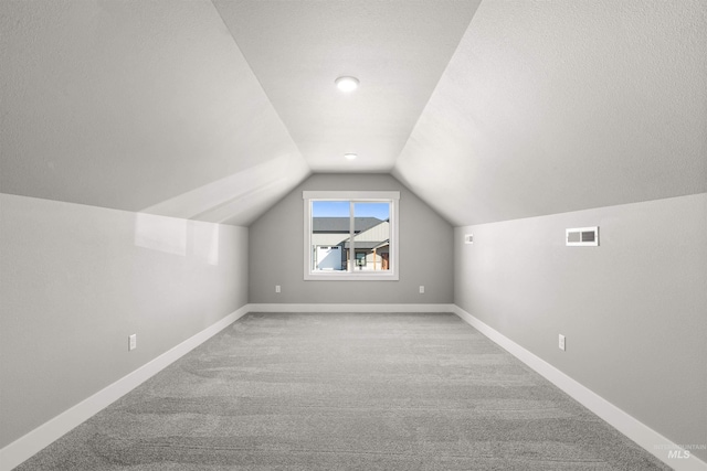 additional living space featuring lofted ceiling, carpet, visible vents, and baseboards