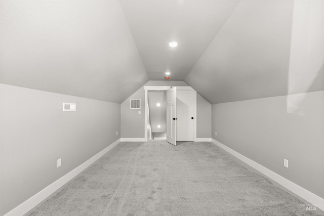 additional living space with lofted ceiling, baseboards, visible vents, and carpet flooring