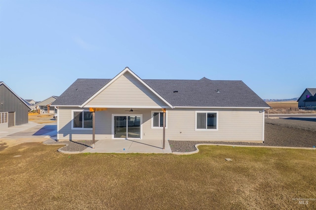 back of house with a yard, a shingled roof, a ceiling fan, and a patio