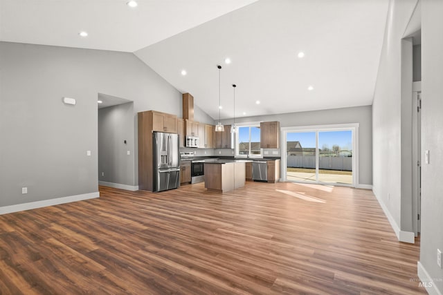 kitchen featuring baseboards, appliances with stainless steel finishes, open floor plan, wood finished floors, and a center island