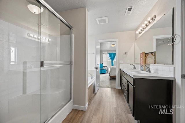 bathroom featuring hardwood / wood-style flooring, a textured ceiling, and separate shower and tub