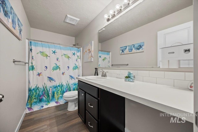 bathroom featuring hardwood / wood-style floors, tasteful backsplash, vanity, a textured ceiling, and toilet