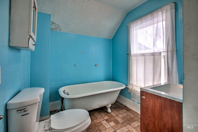 bathroom featuring a washtub, a textured ceiling, vaulted ceiling, toilet, and vanity