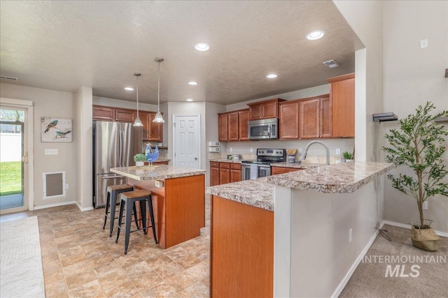 4665 N Beaham Ave, Meridian, ID 83646 - kitchen with stainless steel appliances, a breakfast bar, brown cabinets, recessed lighting, and a peninsula