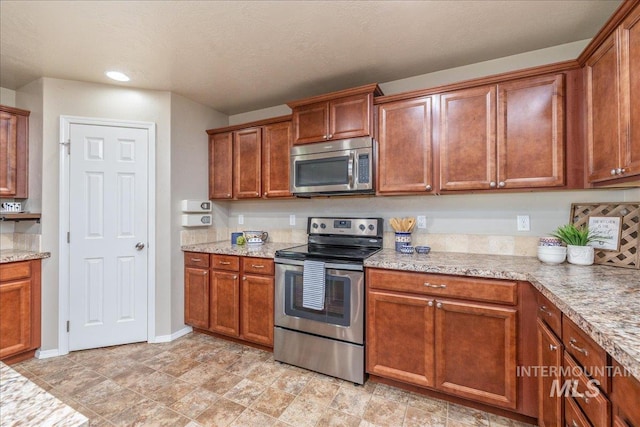 4665 N Beaham Ave, Meridian, ID 83646 - kitchen featuring stainless steel appliances, brown cabinets, baseboards, and light stone countertops