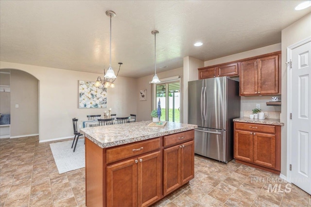 4665 N Beaham Ave, Meridian, ID 83646 - kitchen with freestanding refrigerator, arched walkways, brown cabinetry, pendant lighting, and a kitchen island