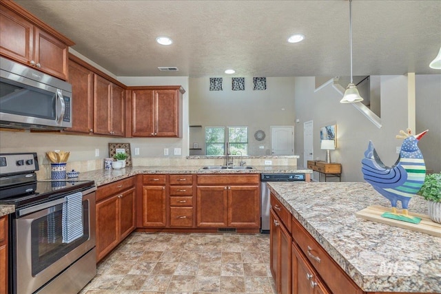 4665 N Beaham Ave, Meridian, ID 83646 - kitchen featuring stainless steel appliances, a sink, brown cabinets, a peninsula, and a textured ceiling
