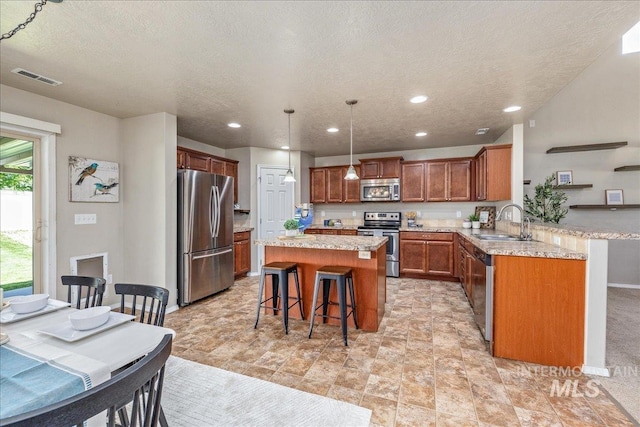 4665 N Beaham Ave, Meridian, ID 83646 - kitchen featuring appliances with stainless steel finishes, a breakfast bar, a sink, a kitchen island, and a textured ceiling