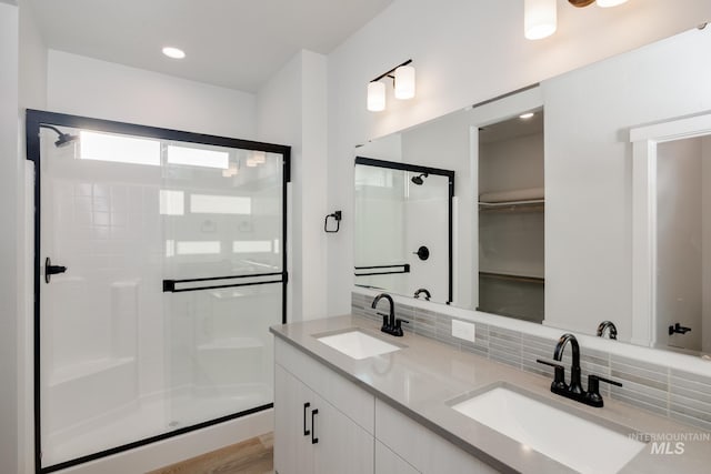 bathroom with a shower with shower door, decorative backsplash, and vanity